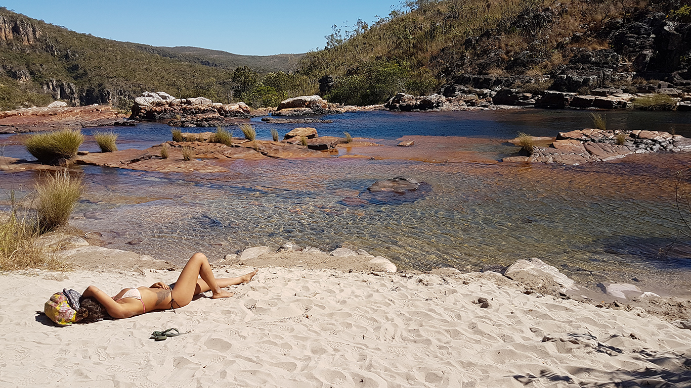 Uma mulher pegando sol em uma das prainhas formadas às margens das cataratas dos Couros na Chapada dos Veadeiros