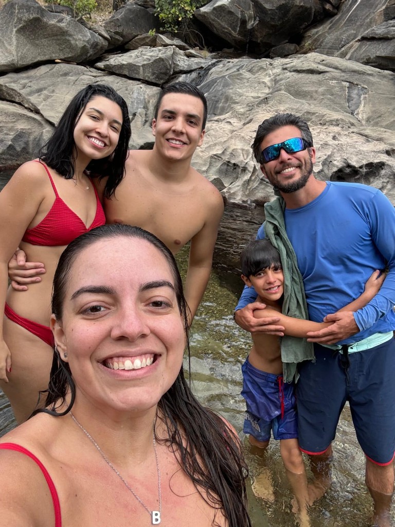 Guide and family in a natural pool between rocks in Chapada dos Veadeiros — human side of tourism with a local driver