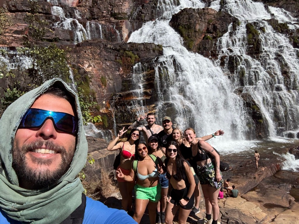 Large group selfie at the base of a stepped waterfall in Chapada dos Veadeiros with a Cadastur guide